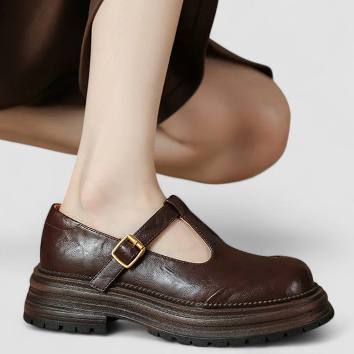 Woman showcasing classic Mary Jane footwear against a plain background.