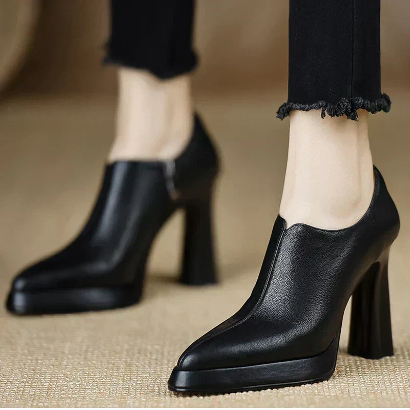 Female model wearing leather look platform pumps with a bold heel on a plain background.