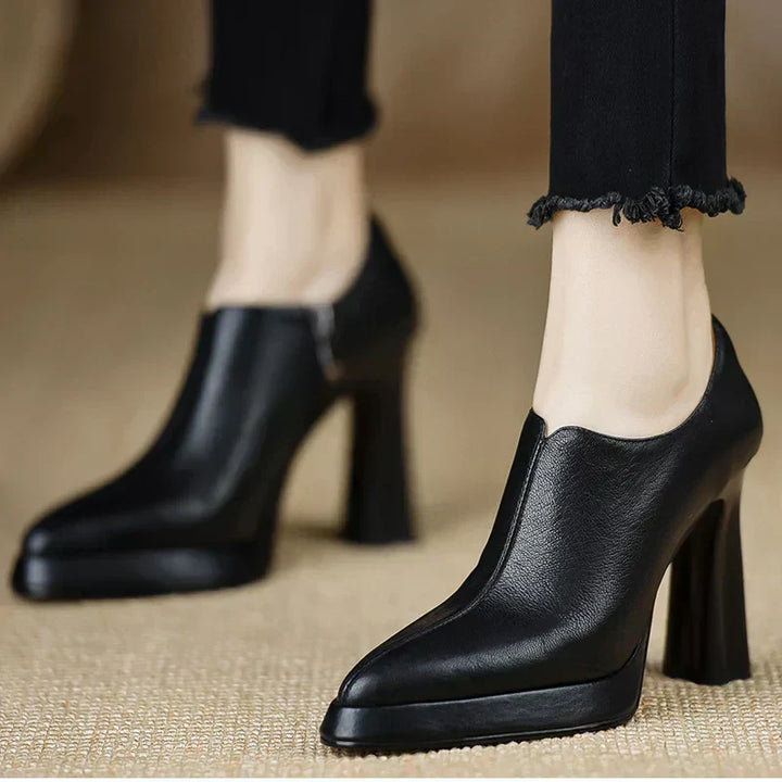 Female model wearing leather look platform pumps with a bold heel on a plain background.