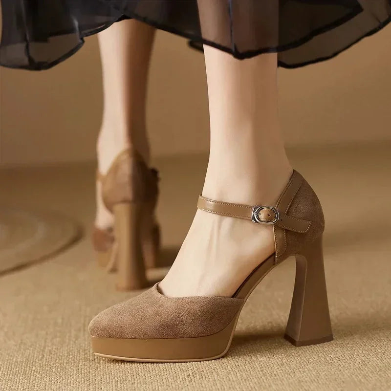 Woman standing in platform block heel shoes with rounded toes on a plain background.