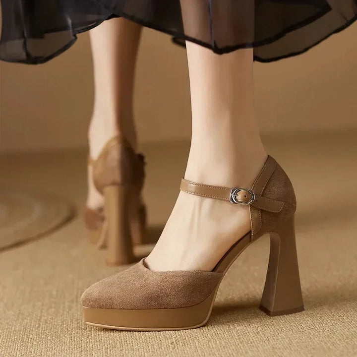Woman standing in platform block heel shoes with rounded toes on a plain background.