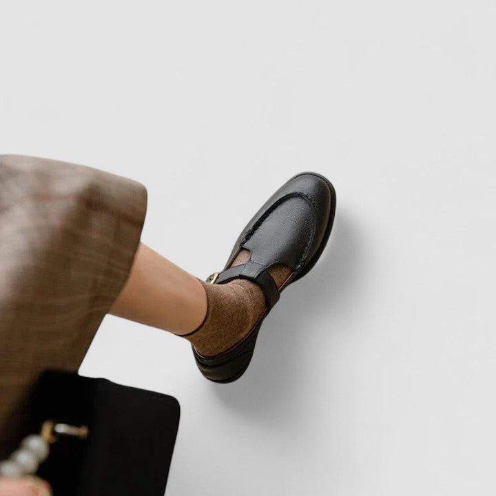Woman showing closed toe strap shoes on a plain background.