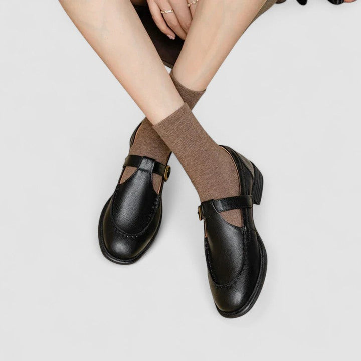 Woman wearing square toe Mary Jane shoes on a plain background.