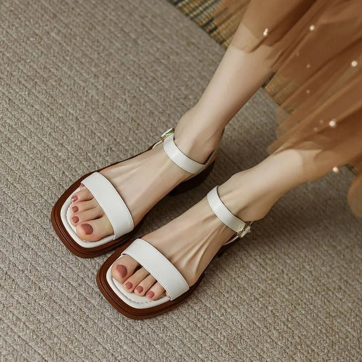 Female model standing in ankle strap sandals on a plain background