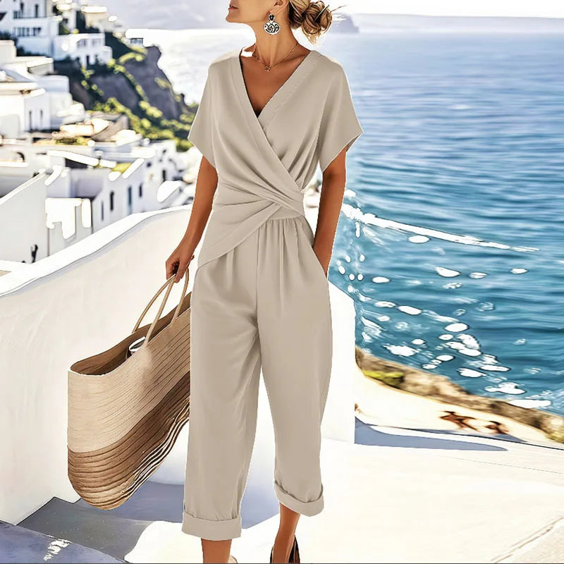 Female wearing a wrap-front two-piece outfit with tapered trousers on a plain background.
