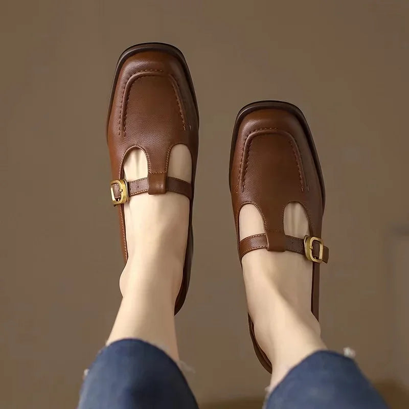 Female model standing in buckle strap shoes with a low block heel.