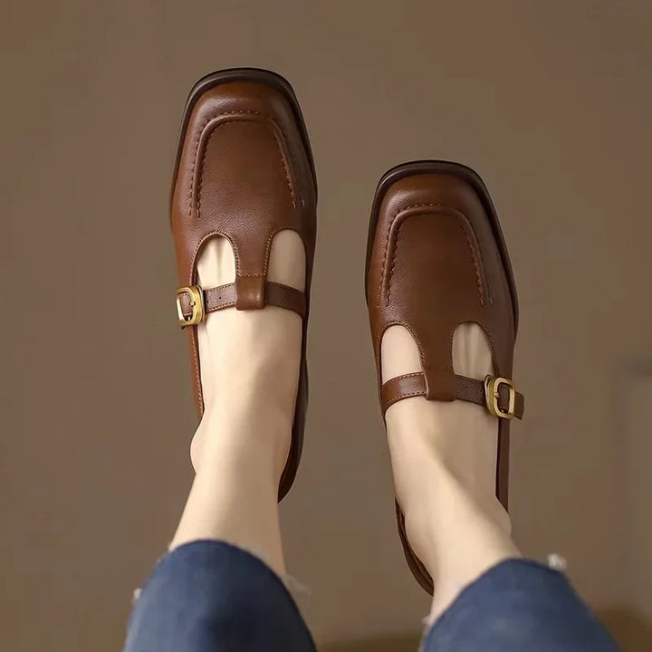 Female model standing in buckle strap shoes with a low block heel.