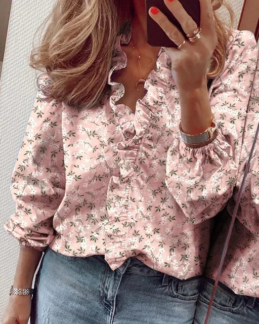  Woman modelling a blouse with ruffle accents and statement sleeves on a plain background.