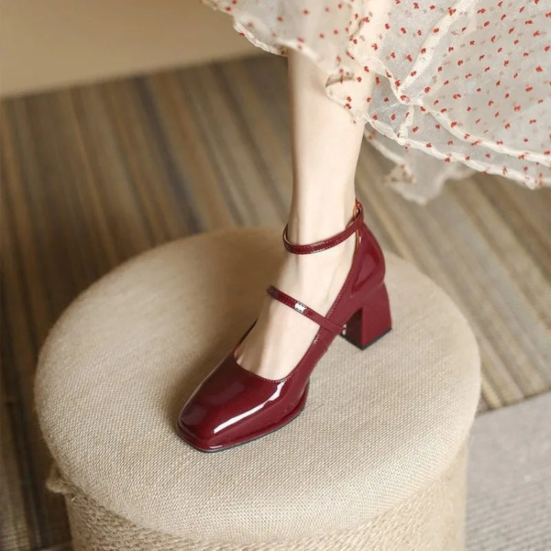 Woman wearing mid-height block heel pumps with ankle straps on a plain background.
