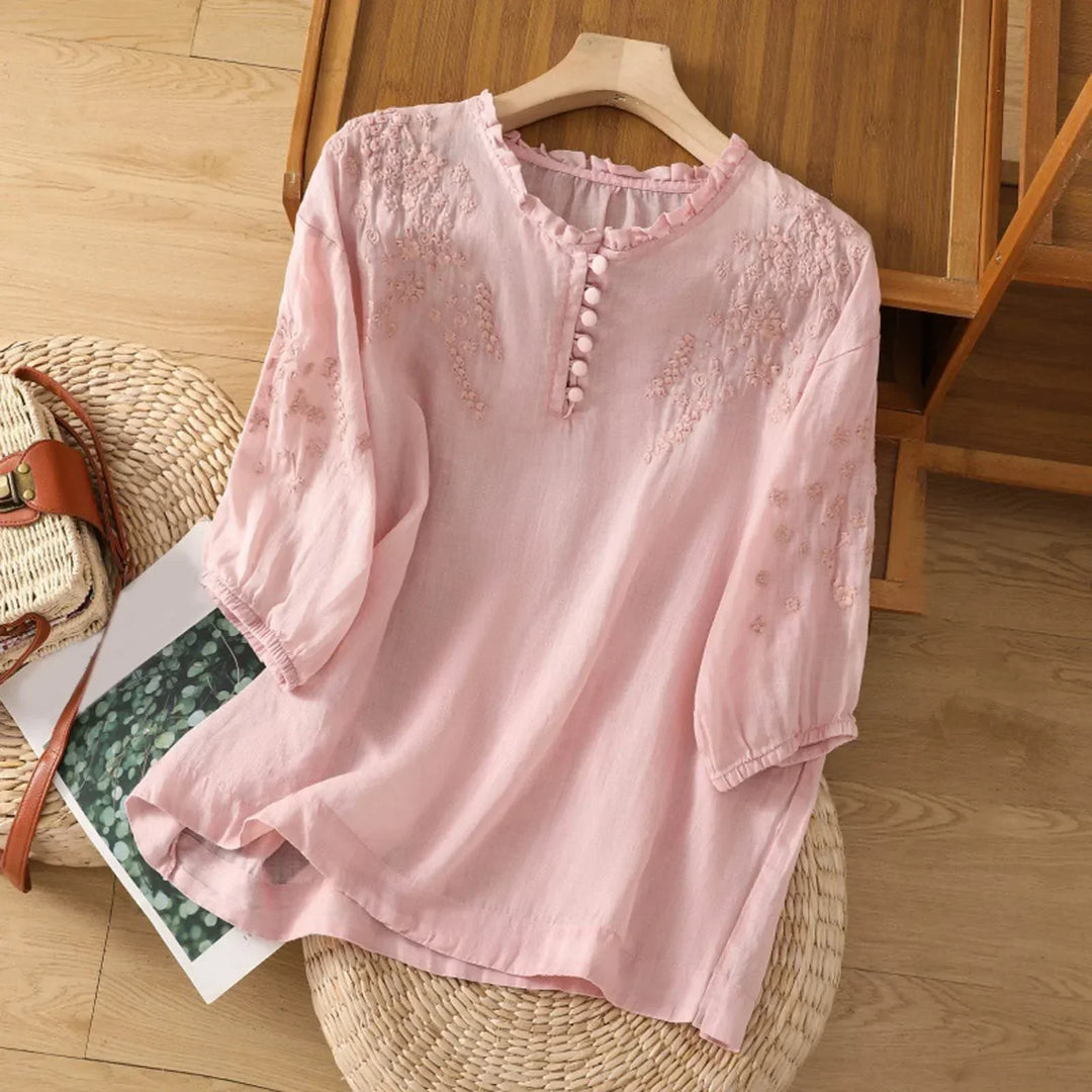 A long-sleeve blouse with detailed embroidery and front buttons.