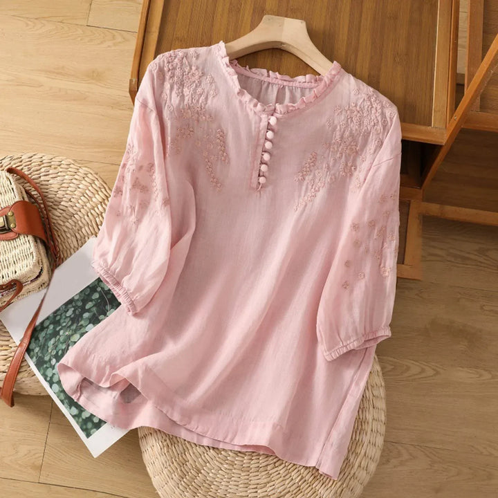 A long-sleeve blouse with detailed embroidery and front buttons.