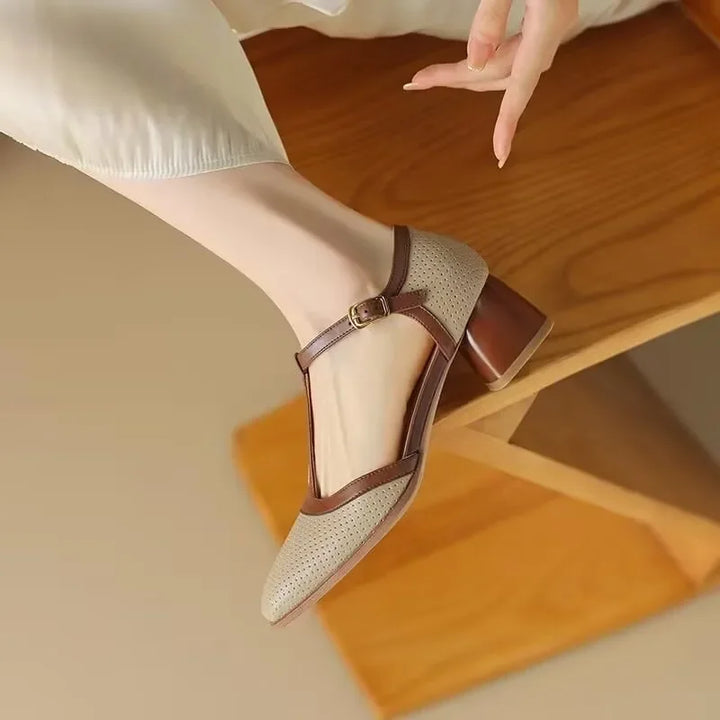 Woman showcasing cream square toe block heels on a plain background.