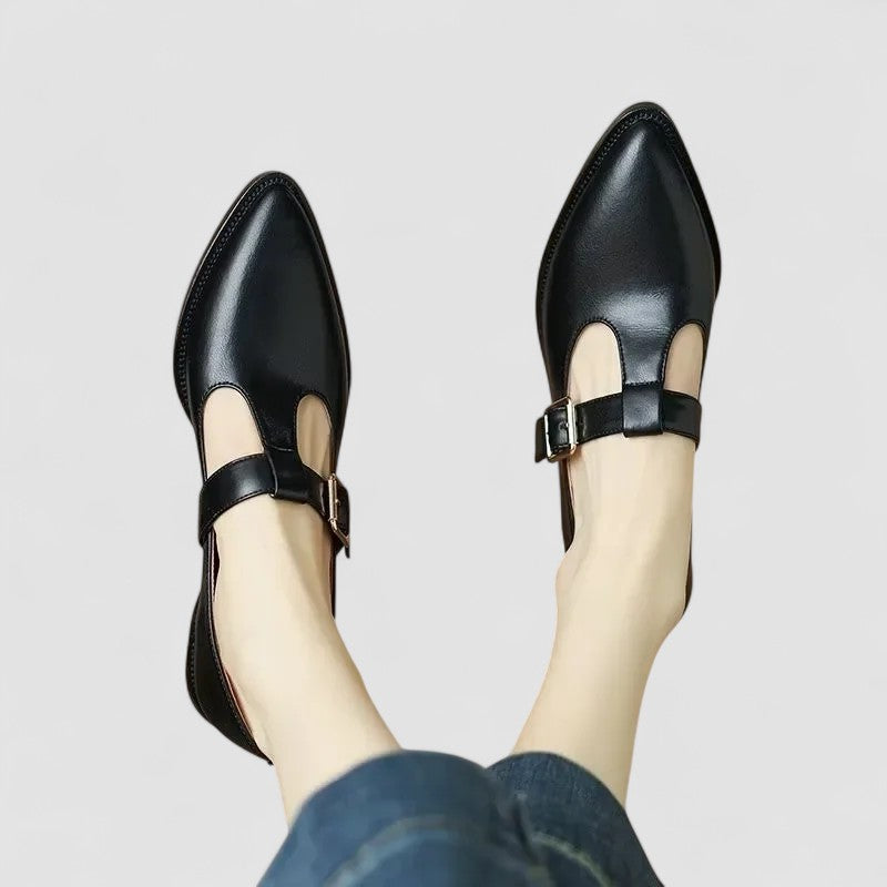 Woman standing in polished dress shoes on a plain background.