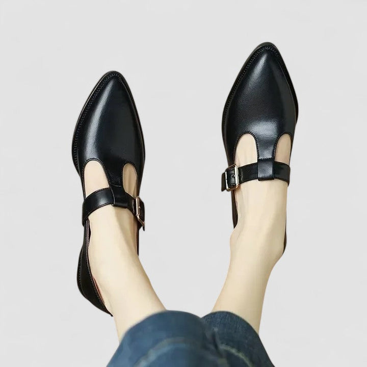 Woman standing in polished dress shoes on a plain background.