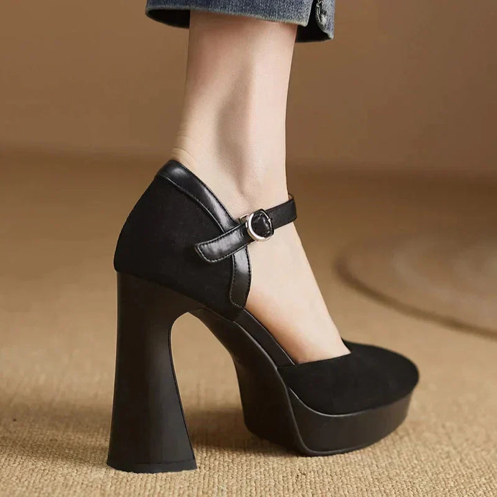 Female model wearing high block heel shoes with a platform front on a plain background.