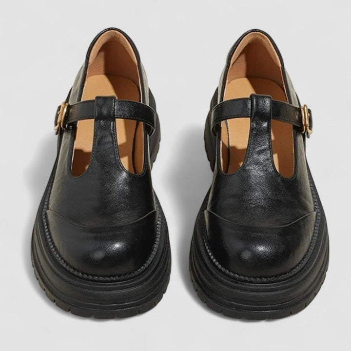 Female wearing strap Mary Jane shoes with a rounded toe on a plain background.