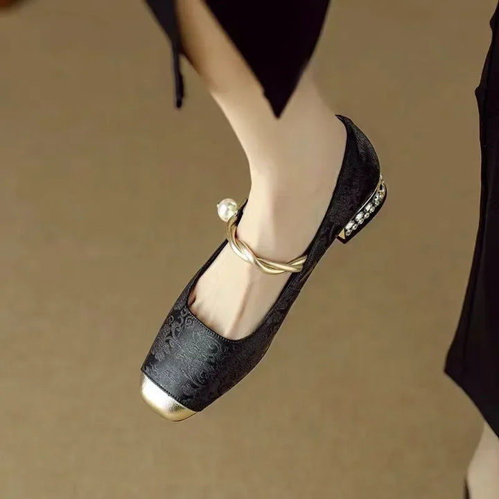 Woman wearing vintage-inspired Mary Jane shoes with pearl accents on a plain background.