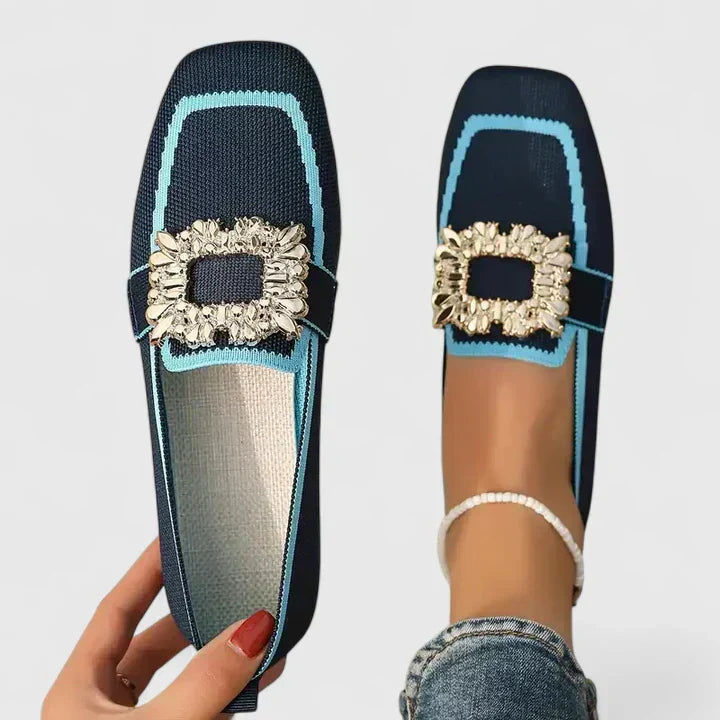 Woman wearing stylish loafers on a plain background.
