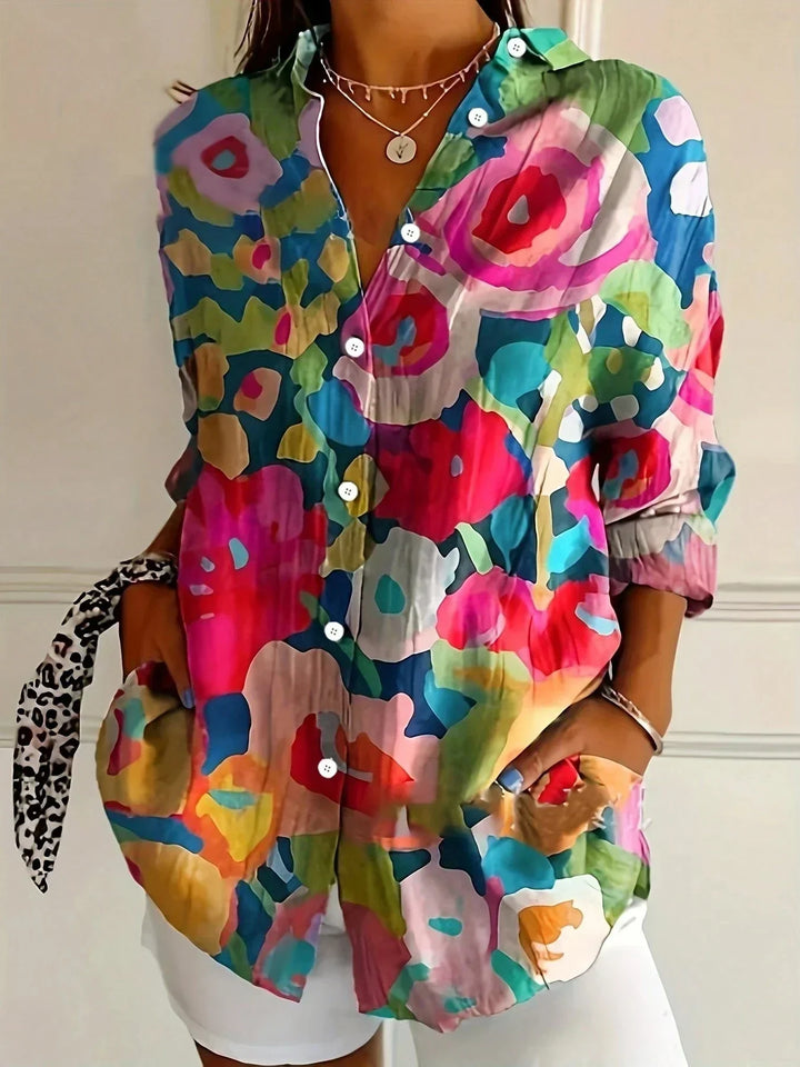 Female model in a vibrant floral casual blouse for summer styling on a plain background.