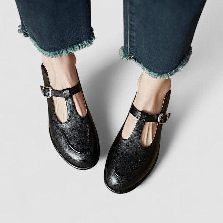 Woman showcasing classic low heel shoes on a plain background.