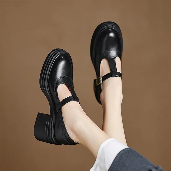 Female model showcasing round toe Mary Jane heels on a plain background.