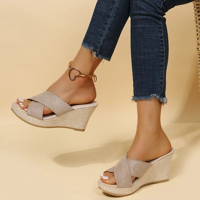 Woman standing in casual summer sandals on a plain background.