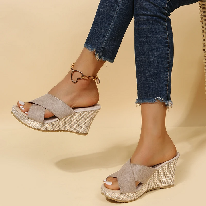 Woman standing in casual summer sandals on a plain background.