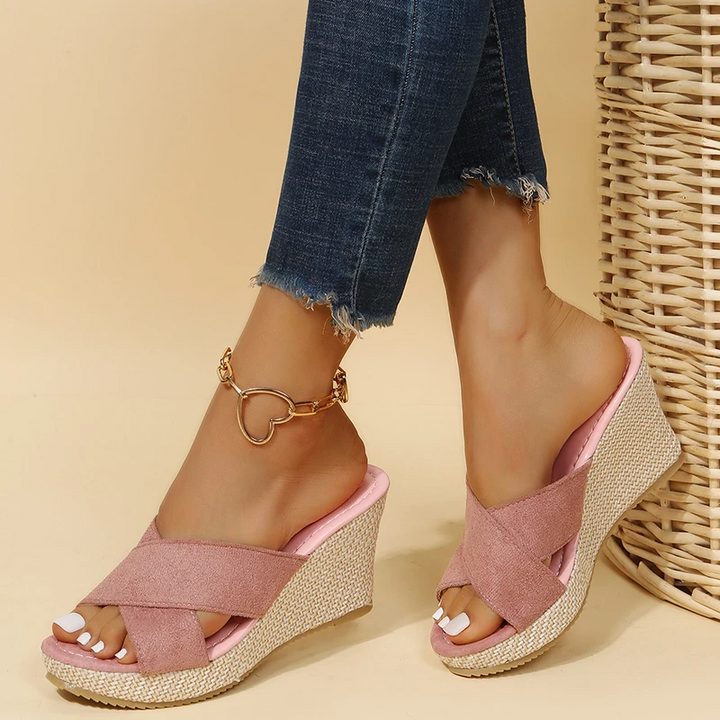 Model wearing open-toe sandals with a clean outfit on a plain background.