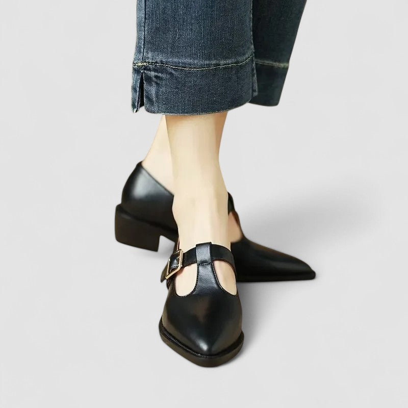 Woman styling graceful shoes with a simple outfit on a plain background.