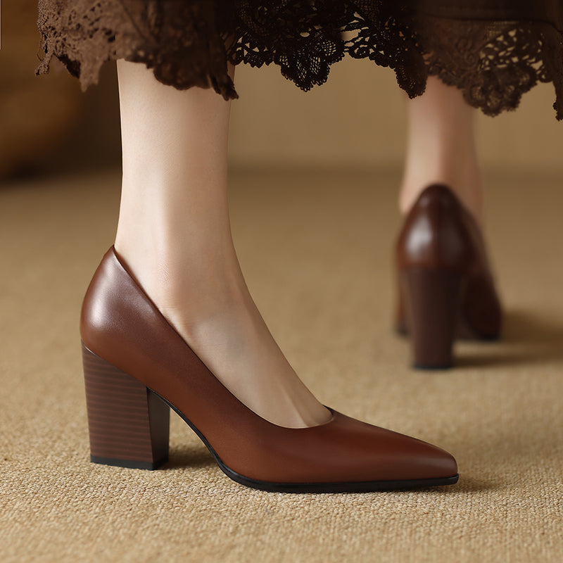 Female wearing pointed toe tan heels with a wide block heel on a plain background.
