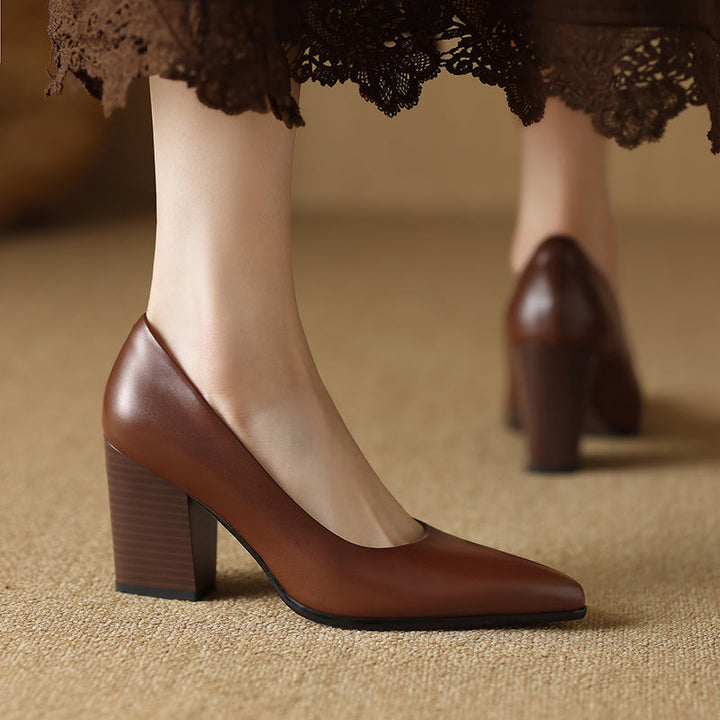 Female wearing pointed toe tan heels with a wide block heel on a plain background.