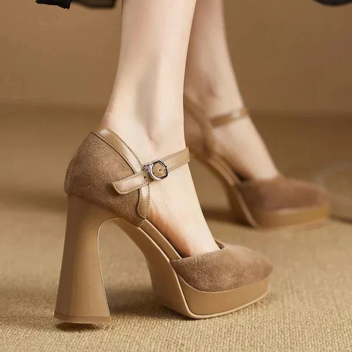 Woman modelling high block heel pumps with slim ankle straps on a plain background.