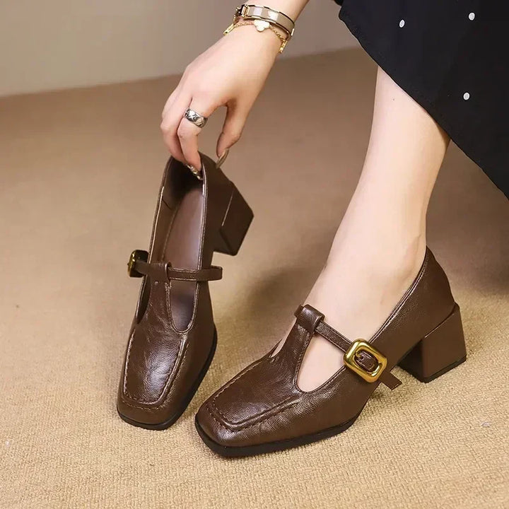 Woman wearing square toe Mary Jane heels on a plain background.