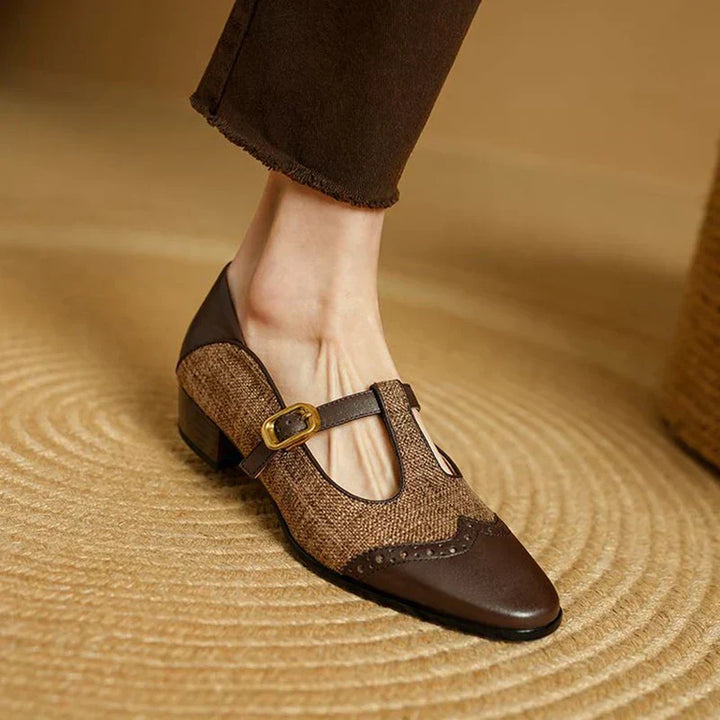 Woman wearing retro T-strap shoes with contrast panels on a plain background.