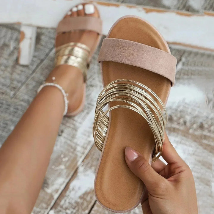 Woman wearing stylish everyday sandals with a plain background.