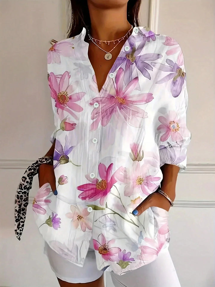  Woman wearing a colourful patterned blouse with a flowing silhouette on a plain background.
