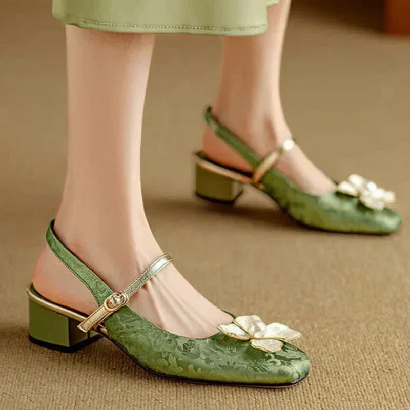 Woman modelling square toe floral heels on a plain background.