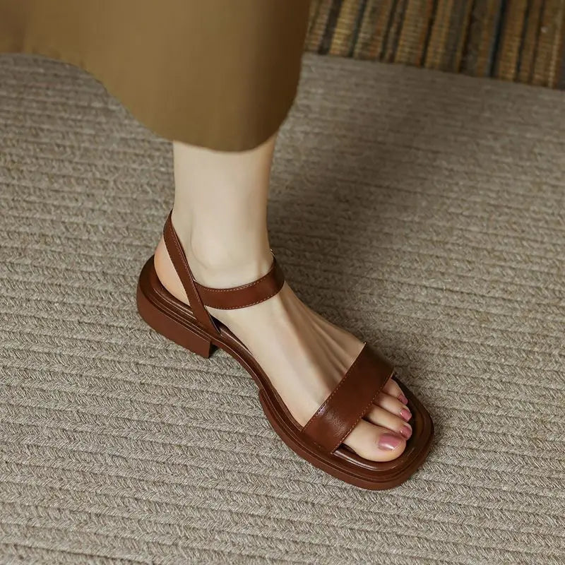 Model wearing open-toe block heel sandals on a plain background