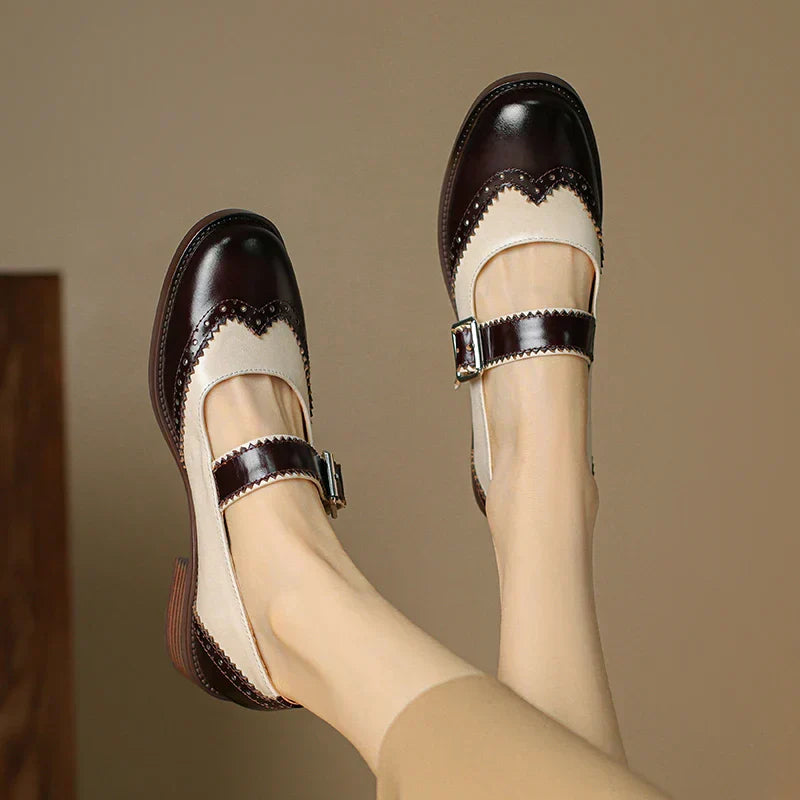 Woman wearing low block heel Mary Jane shoes on a plain background.