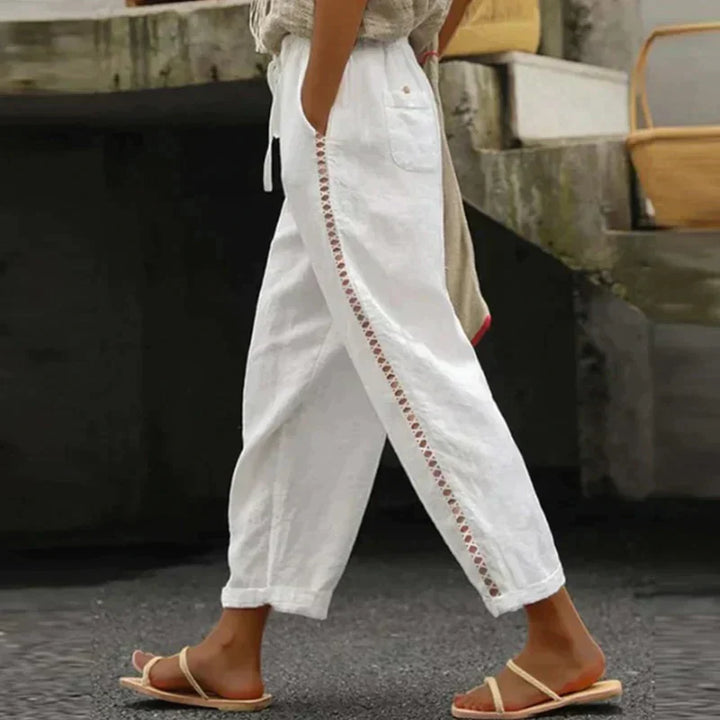Female model wearing wide-leg trousers with a drawstring waist and side trim detail against a plain background.