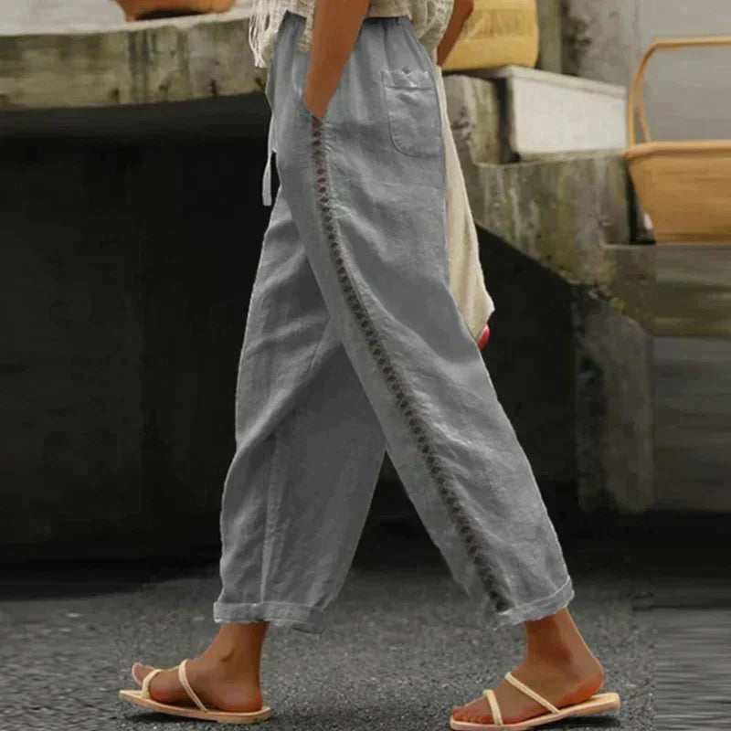 Woman showcasing relaxed wide-leg trousers with an adjustable waist on a plain background.
