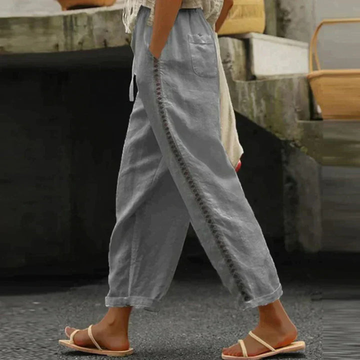 Woman showcasing relaxed wide-leg trousers with an adjustable waist on a plain background.

