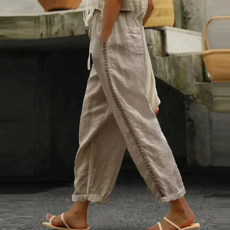 Woman wearing drawstring waist trousers with a relaxed wide-leg silhouette against a plain backdrop.