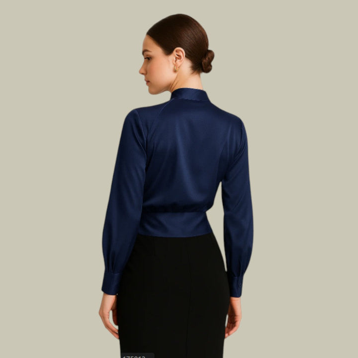 Woman wearing a polished V-neck blouse with defined waist detail on a plain background.