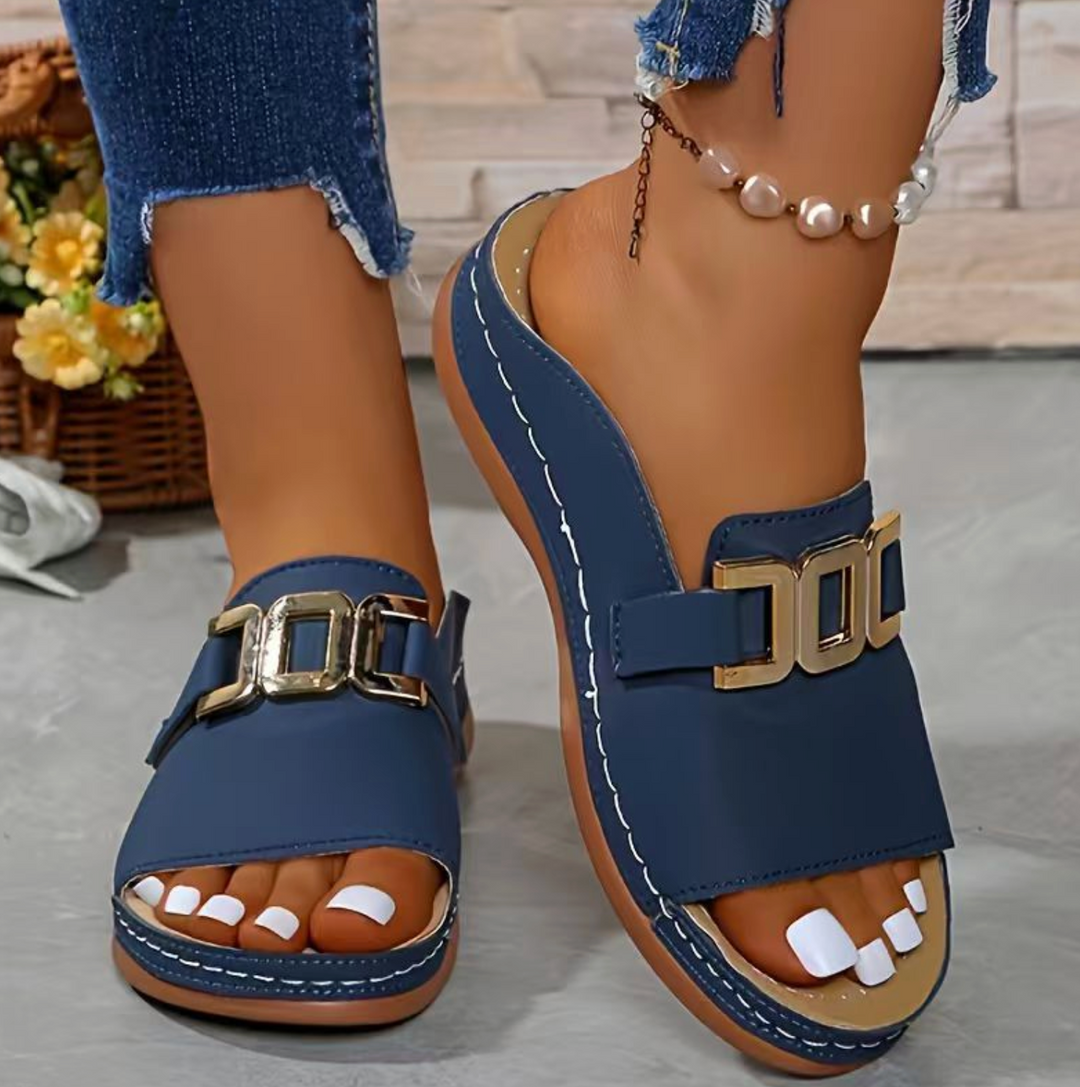 Female wearing buckle slide sandals on a plain background.