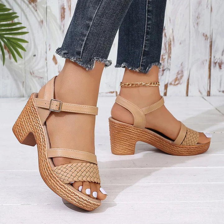  Woman wearing ankle strap platform sandals on a clean plain background.