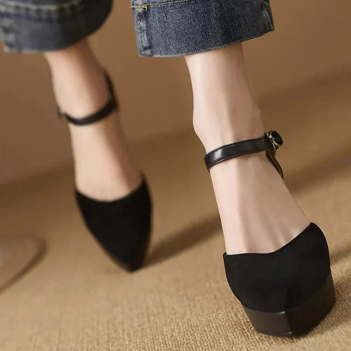 Woman wearing elegant ankle strap pumps with a raised platform sole on a plain background.