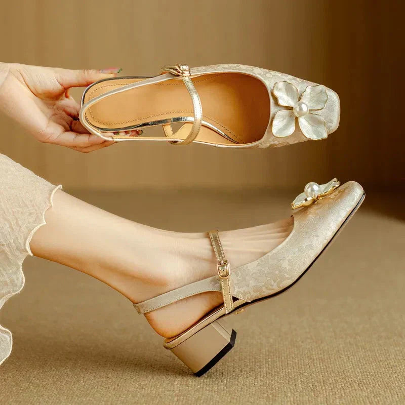 Woman wearing feminine slingback pumps with flower detail on a plain background.