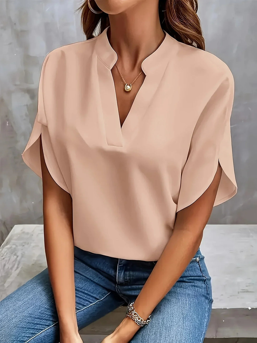 Female in a stylish blouse with soft drape and cap sleeves.