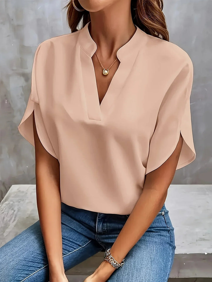Female in a stylish blouse with soft drape and cap sleeves.